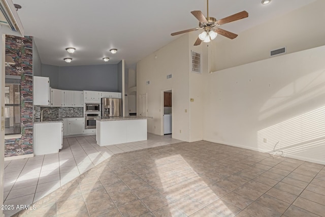 unfurnished living room with high vaulted ceiling, light tile patterned floors, and ceiling fan