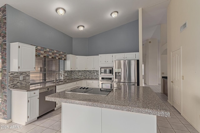 kitchen with light tile patterned floors, stainless steel appliances, white cabinetry, and a center island