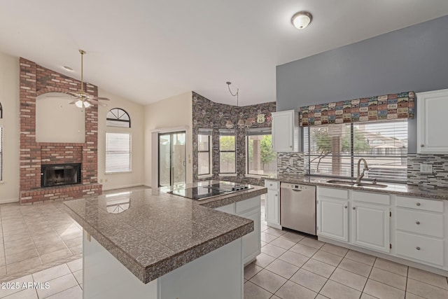 kitchen featuring hanging light fixtures, dishwasher, a fireplace, a kitchen island, and white cabinetry