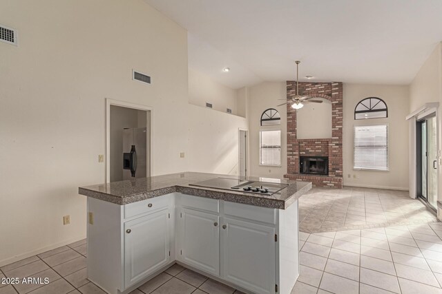 kitchen with a fireplace, a center island, white cabinets, and stainless steel refrigerator with ice dispenser