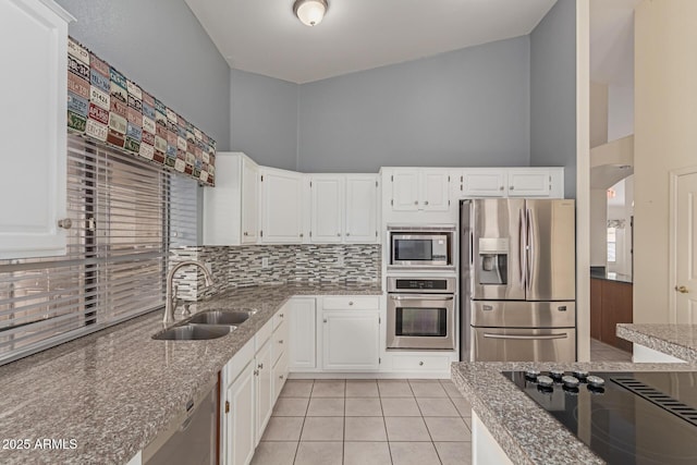 kitchen with sink, appliances with stainless steel finishes, white cabinets, and dark stone counters