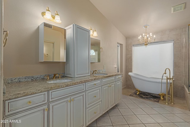 bathroom featuring tile patterned floors, vanity, a bathtub, and an inviting chandelier