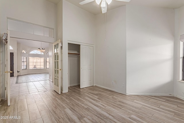 unfurnished bedroom featuring a notable chandelier, light hardwood / wood-style floors, a high ceiling, and a closet