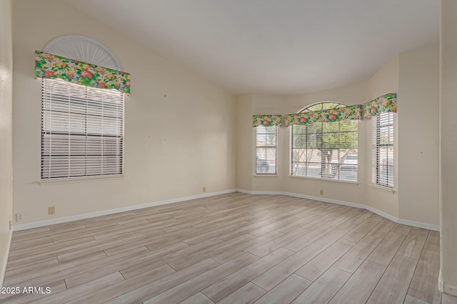 spare room featuring light wood-type flooring and lofted ceiling