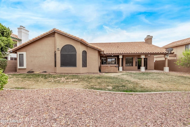 back of house with a patio area, a hot tub, and a lawn