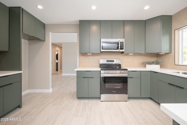 4506 W Golden Ln, Glendale, AZ 85302 - kitchen featuring backsplash, green cabinets, and appliances with stainless steel finishes
