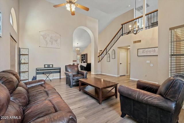 living room with ceiling fan with notable chandelier, light wood-type flooring, and high vaulted ceiling