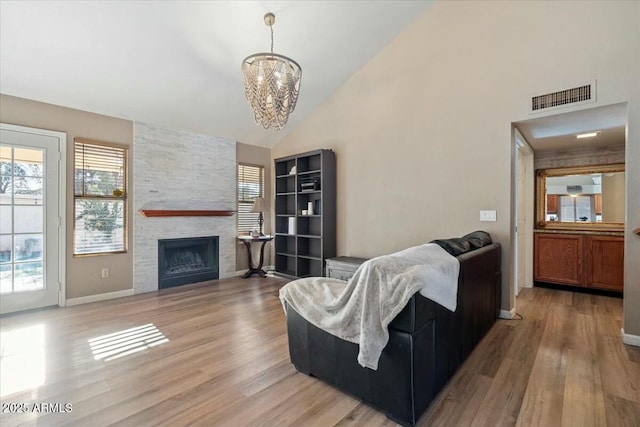 living room with a fireplace, hardwood / wood-style floors, vaulted ceiling, and an inviting chandelier