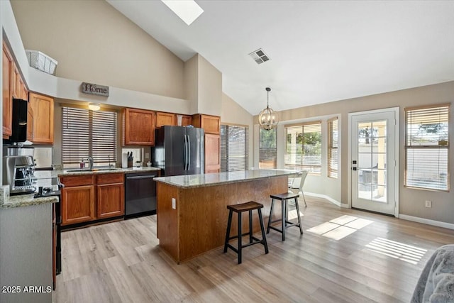 kitchen featuring a center island, hanging light fixtures, black dishwasher, a notable chandelier, and stainless steel fridge