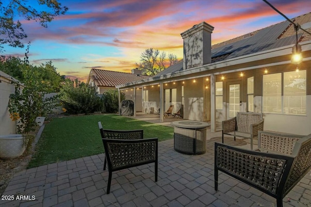 patio terrace at dusk featuring an outdoor living space and a lawn