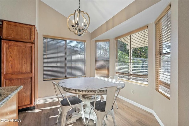 dining space featuring light wood-type flooring, vaulted ceiling, and a notable chandelier