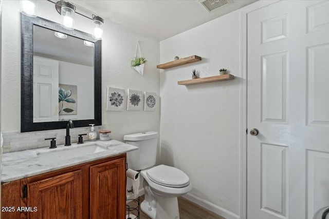 bathroom with decorative backsplash, hardwood / wood-style floors, vanity, and toilet