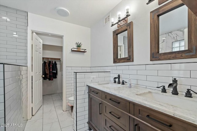 bathroom with vanity, tile walls, and toilet