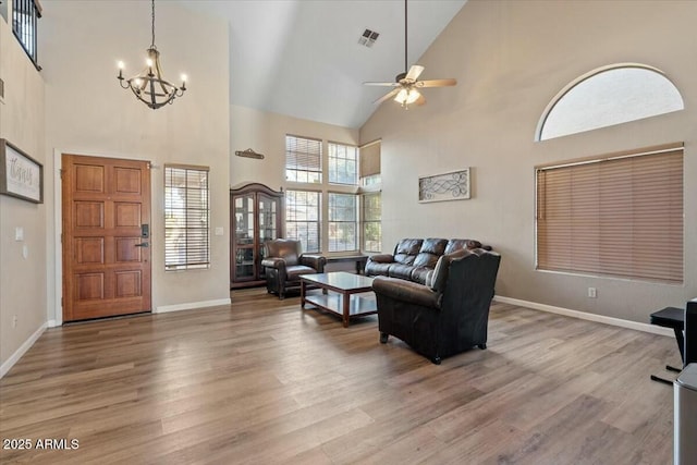 living room featuring hardwood / wood-style floors, ceiling fan with notable chandelier, and a towering ceiling