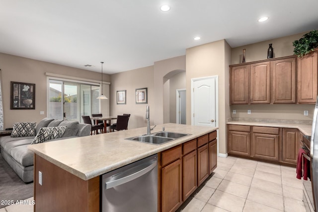 kitchen with stainless steel dishwasher, sink, decorative light fixtures, light tile patterned flooring, and an island with sink