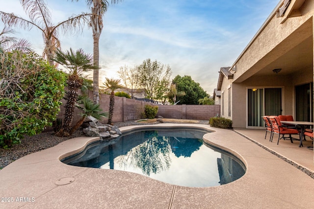 pool at dusk with a patio area