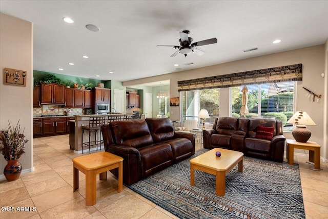 living room with light tile patterned floors and ceiling fan with notable chandelier