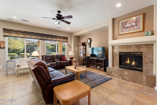 tiled living room featuring ceiling fan and a fireplace