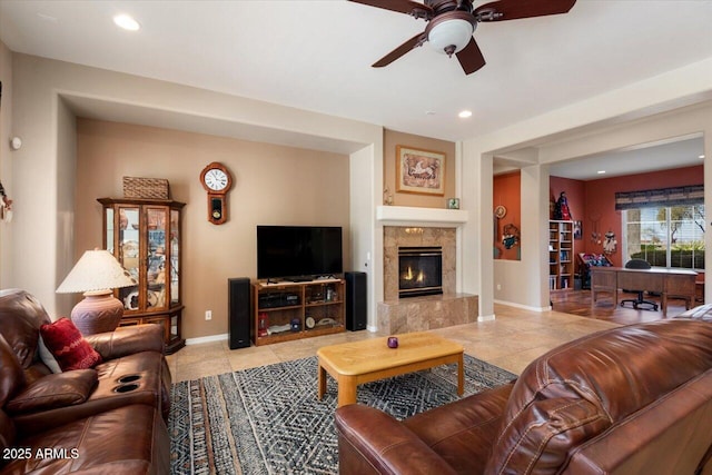 living room featuring light tile patterned flooring, ceiling fan, and a tiled fireplace