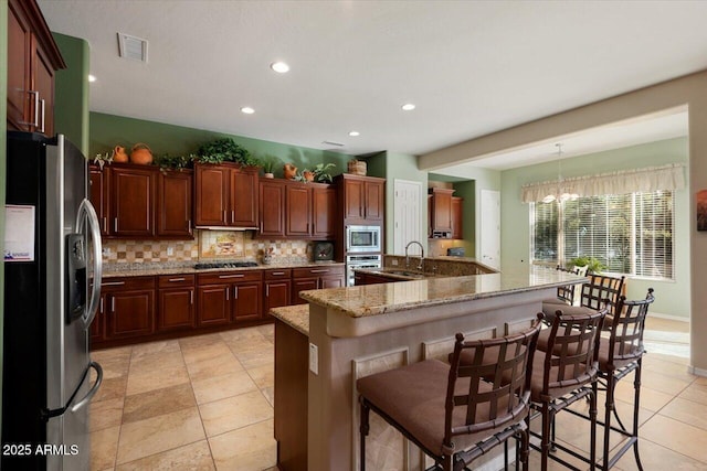 kitchen with an inviting chandelier, decorative light fixtures, appliances with stainless steel finishes, a large island, and a breakfast bar area