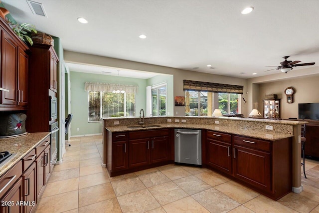 kitchen with light stone counters, ceiling fan with notable chandelier, stainless steel appliances, sink, and decorative light fixtures