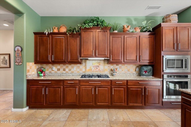 kitchen featuring tasteful backsplash, light stone countertops, and stainless steel appliances