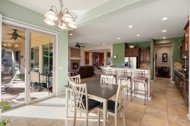 dining space featuring ceiling fan with notable chandelier