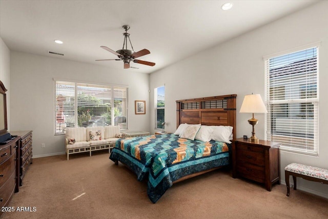 bedroom with multiple windows, ceiling fan, and light carpet