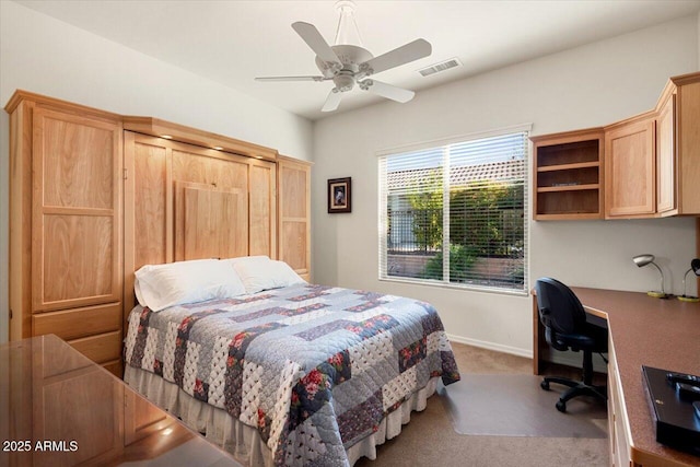 bedroom with ceiling fan, carpet floors, and built in desk