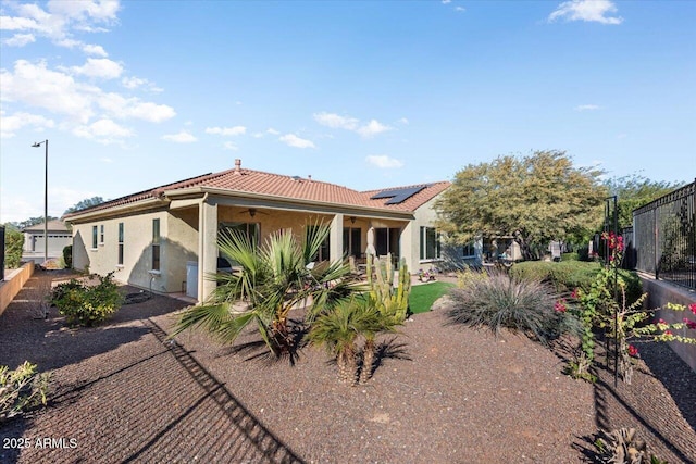 view of front of house featuring solar panels and ceiling fan