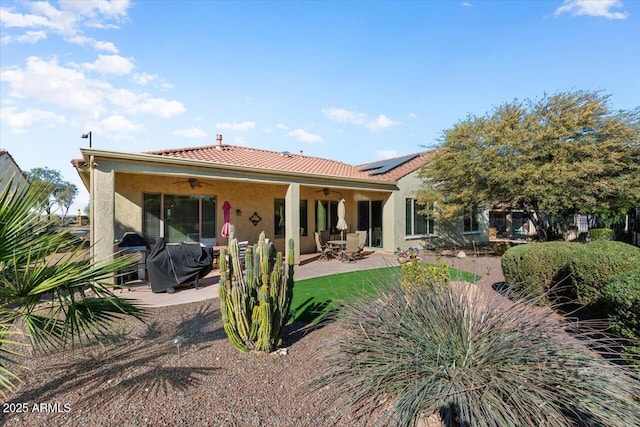 rear view of property with ceiling fan, a patio, and solar panels