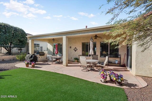 back of property with a yard, ceiling fan, and a patio area