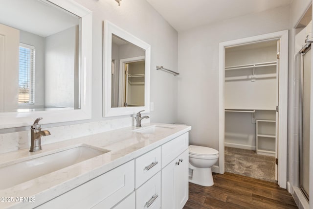 bathroom with wood-type flooring, toilet, a shower with shower door, and vanity