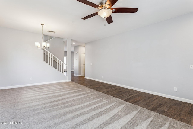 unfurnished living room with ceiling fan with notable chandelier and dark hardwood / wood-style flooring