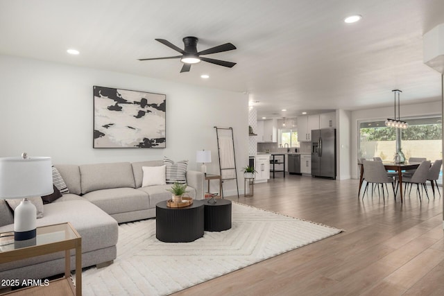living area with a ceiling fan, wood finished floors, and recessed lighting