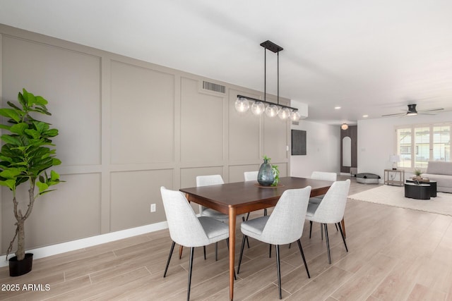 dining space with a decorative wall, light wood-style floors, a ceiling fan, and recessed lighting