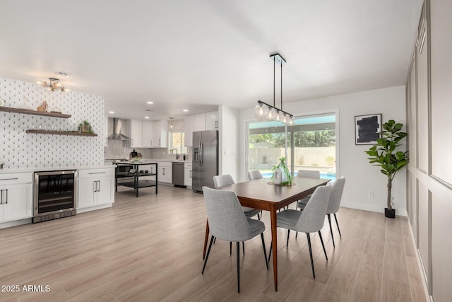 dining room with wine cooler, light wood-style floors, healthy amount of natural light, baseboards, and recessed lighting