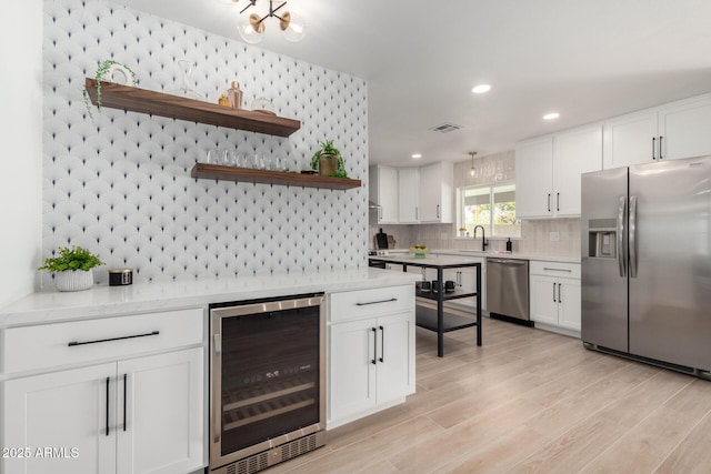 kitchen featuring appliances with stainless steel finishes, beverage cooler, open shelves, a sink, and backsplash