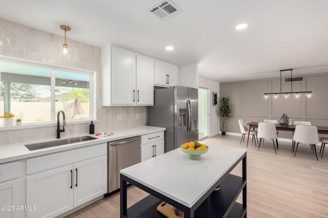 kitchen featuring a sink, appliances with stainless steel finishes, backsplash, light countertops, and white cabinetry