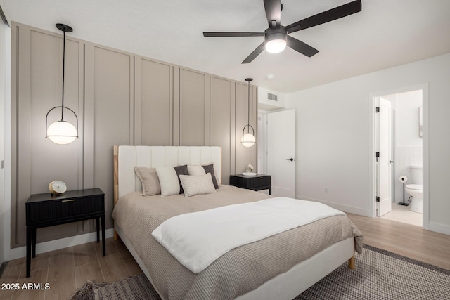 bedroom featuring light wood-style flooring, baseboards, and connected bathroom