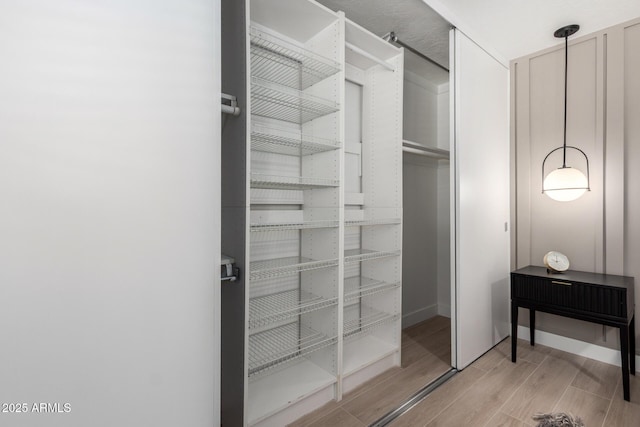 walk in closet with light wood-style floors