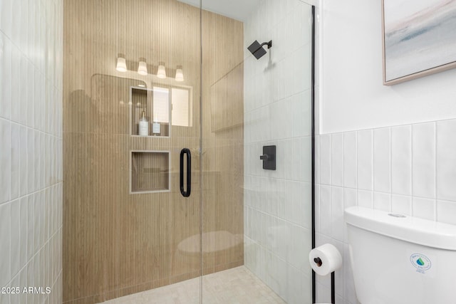 bathroom featuring a stall shower, toilet, and tile walls