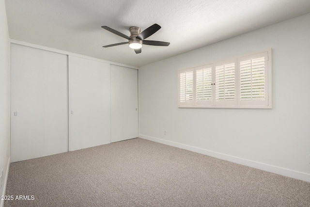 unfurnished bedroom featuring carpet floors, a closet, ceiling fan, and baseboards