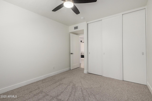 unfurnished bedroom with carpet floors, a closet, baseboards, and a ceiling fan
