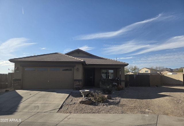 view of front of house featuring stucco siding, fence, a garage, stone siding, and driveway