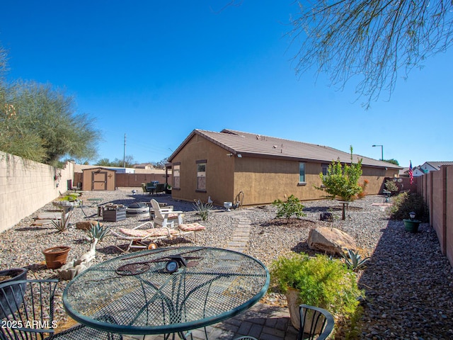 exterior space featuring an outbuilding, a fenced backyard, a vegetable garden, stucco siding, and a storage unit