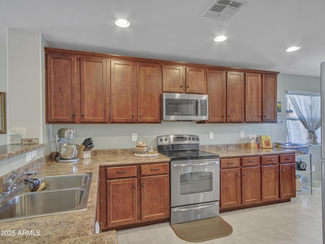 kitchen with light stone counters, recessed lighting, stainless steel appliances, a sink, and visible vents