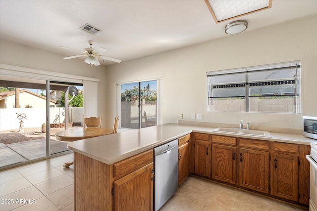 kitchen featuring visible vents, a peninsula, light countertops, a sink, and appliances with stainless steel finishes