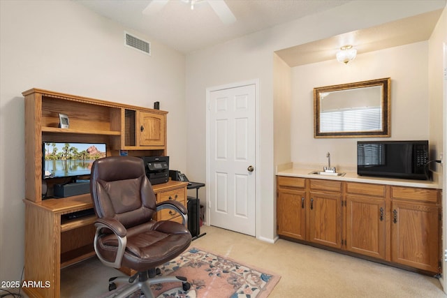 office space with visible vents, a sink, a ceiling fan, and light carpet