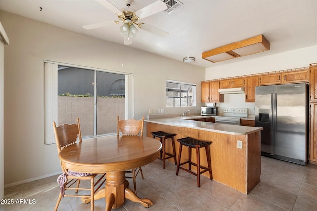 kitchen with a sink, stainless steel appliances, a peninsula, under cabinet range hood, and visible vents